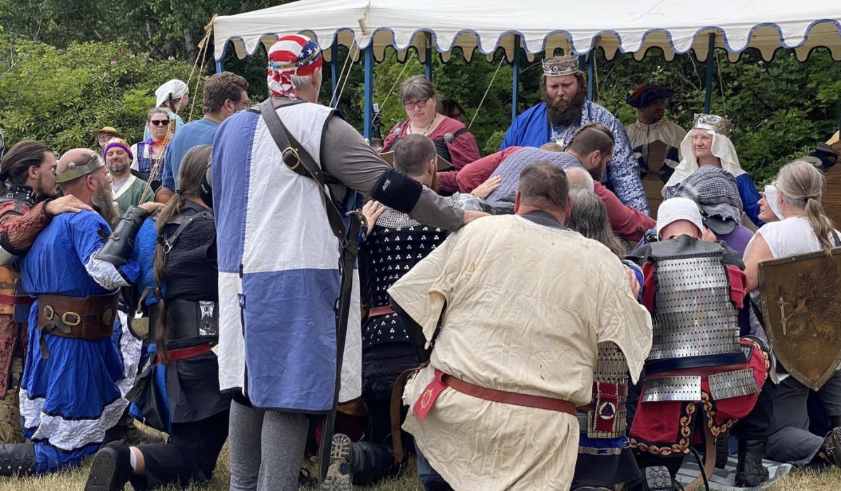people in medieval clothing and armor huddled around a king